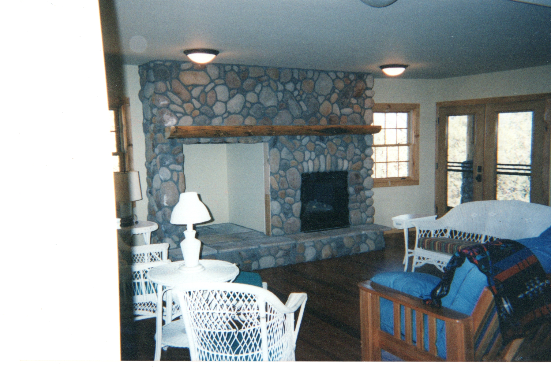 Living room with a full height river rock fireplace and a reclaimed timber mantel